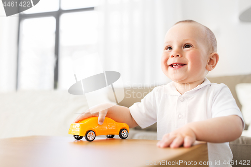 Image of happy baby boy playing with toy car at home