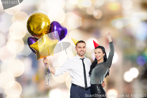 Image of happy couple with party caps and balloons