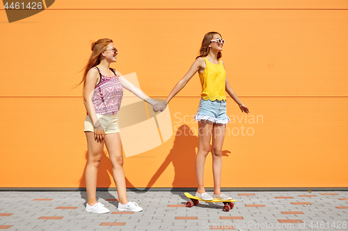 Image of teenage girls riding skateboard on city street