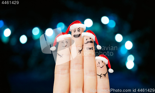 Image of close up of four fingers in santa hats over lights