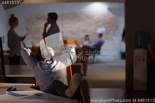 Image of businessman sitting with legs on desk at office