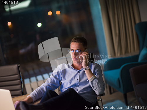 Image of businessman using mobile phone in dark office