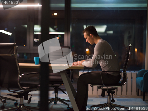 Image of man working on laptop in dark office