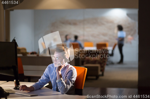 Image of man using mobile phone in dark office