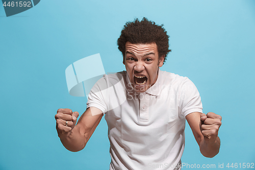 Image of The young emotional angry man screaming on blue studio background