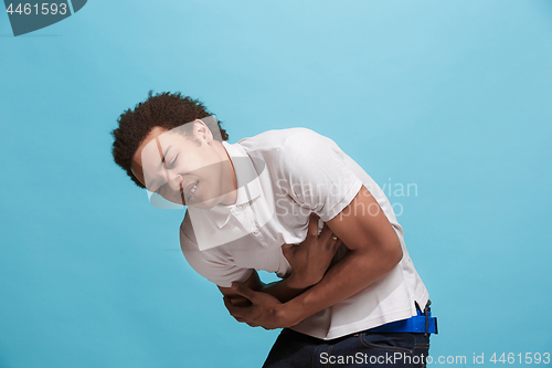 Image of Young man overwhelmed with a pain in the stomach .
