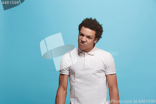 Image of The young emotional angry man screaming on blue studio background