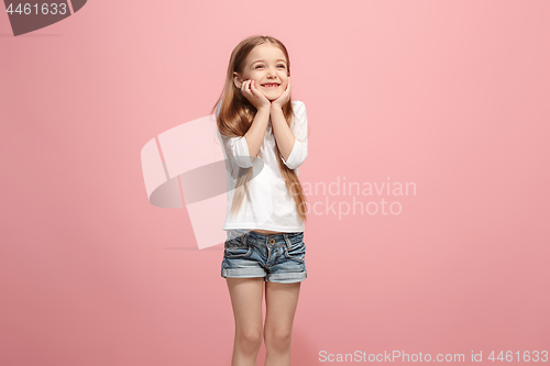 Image of The happy teen girl standing and smiling against pink background.