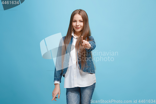 Image of The happy teen girl pointing to you, half length closeup portrait on blue background.