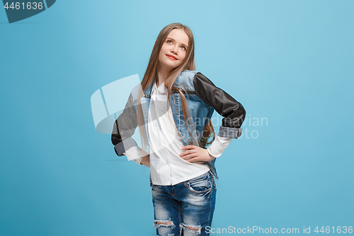 Image of The happy teen girl standing and smiling against blue background.