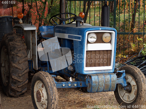 Image of Old blue tractor in the shed with mud