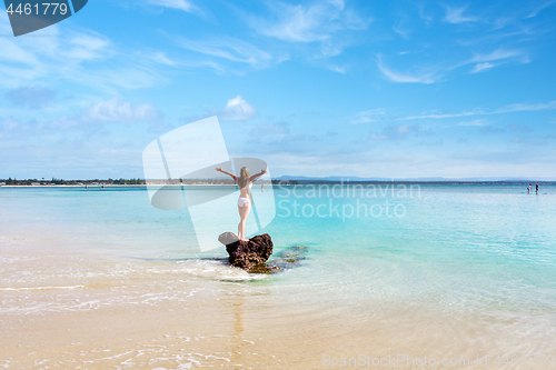 Image of Woman wearing white swimsuit at idyllic beach feeling good