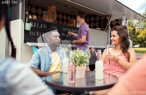 Image of friends with drinks sitting at table at food truck