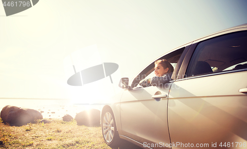 Image of happy teenage girl or young woman in car