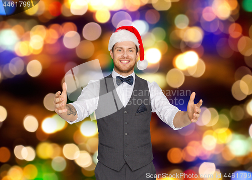 Image of happy man in santa hat holding something imaginary