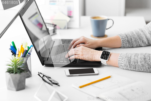 Image of designer with smart watch and laptop at office