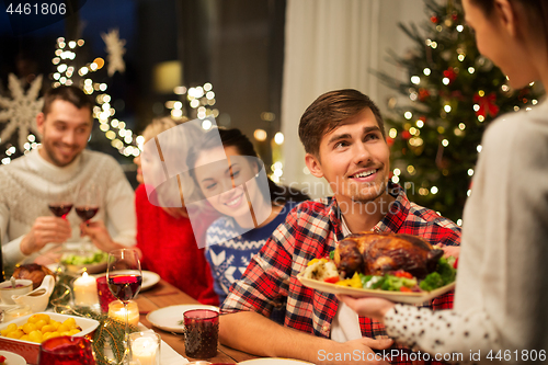 Image of happy friends having christmas dinner at home