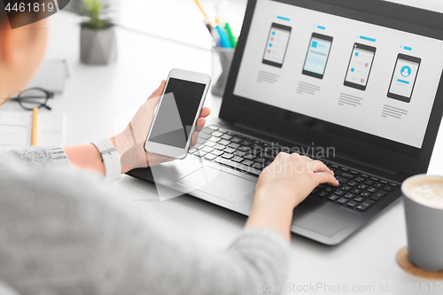 Image of web designer with smartphone and laptop at office