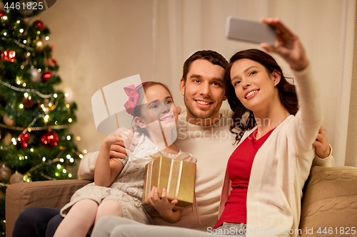 Image of happy family with christmas present at home