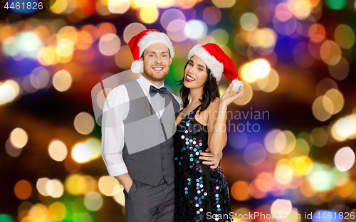 Image of happy couple in santa hats at christmas party