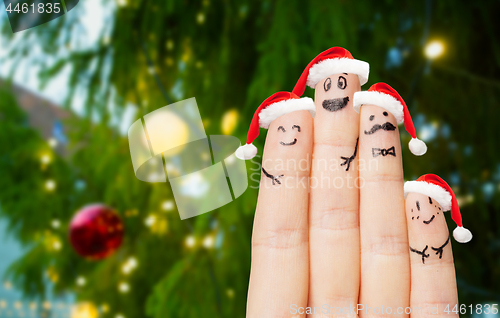 Image of fingers in santa hats over christmas tree