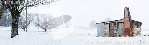 Image of Rustic timber cabin with chimney in snowy winter landscape