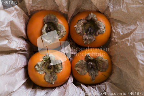 Image of Four kaki fruits (persimmon) in box. Top view