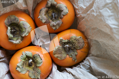 Image of Four kaki fruits (persimmon) in box. Top view