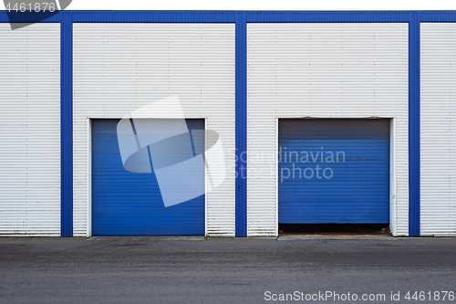 Image of White Industrial warehouse with blue door for trucks.