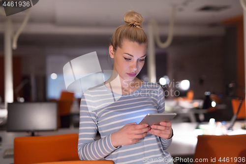 Image of woman working on digital tablet in night office