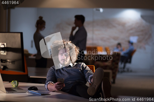 Image of businessman sitting with legs on desk at office