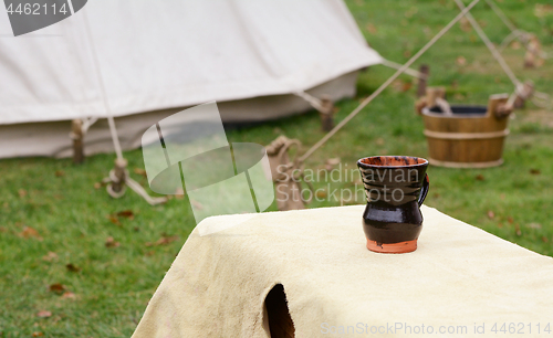 Image of Glazed clay cup on a bench in a Medieval camp