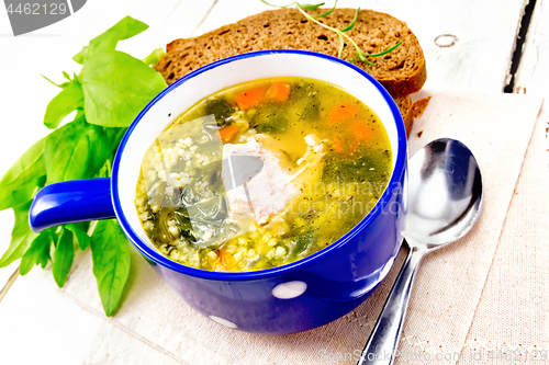 Image of Soup with couscous and spinach in blue bowl on board