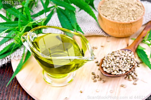 Image of Oil hemp in sauceboat with grain on dark board