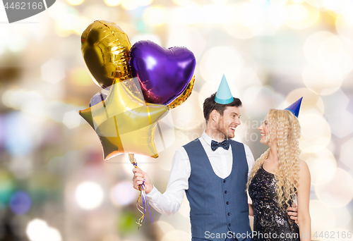 Image of happy couple with party caps and balloons