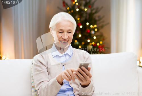 Image of senior woman with smartphone at home on christmas