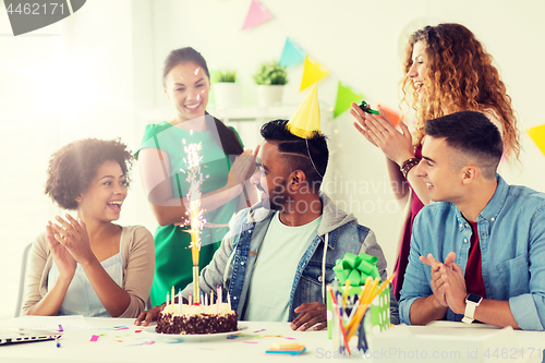 Image of team greeting colleague at office birthday party