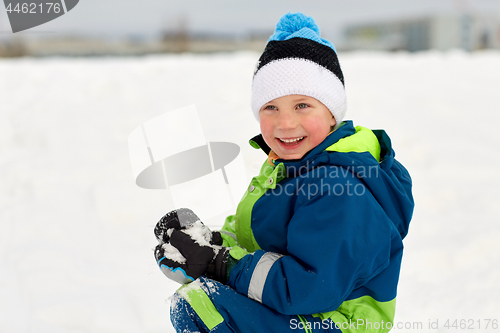 Image of happy little boy playing with snow in winter