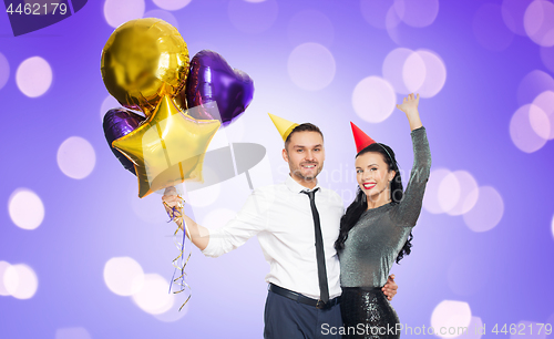 Image of happy couple with party caps and balloons