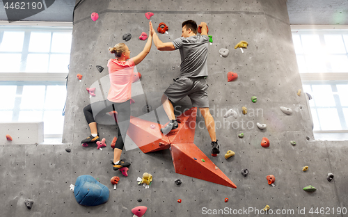 Image of man and woman climbing a wall at indoor gym