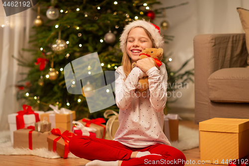 Image of smiling girl in santa hat with christmas gift