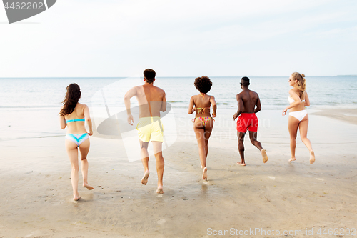 Image of happy friends running on summer beach