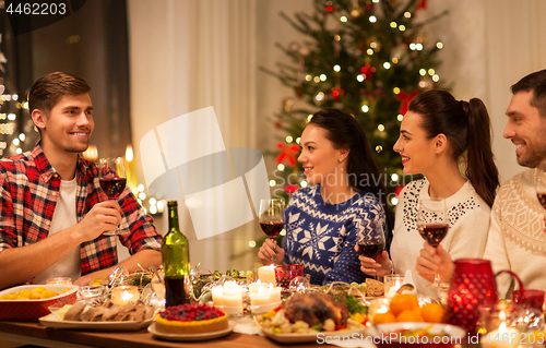 Image of happy friends drinking red wine at christmas party