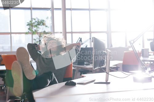 Image of businessman sitting with legs on desk