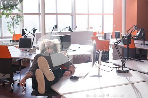 Image of businessman sitting with legs on desk