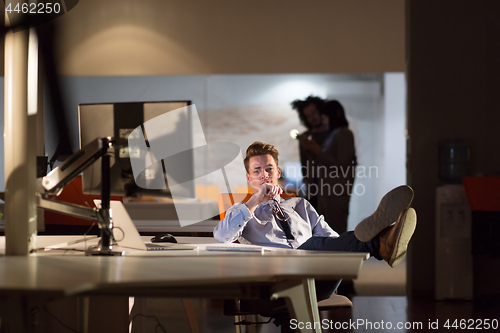 Image of businessman sitting with legs on desk at office