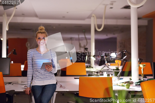 Image of woman working on digital tablet in night office