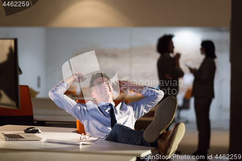 Image of businessman sitting with legs on desk at office