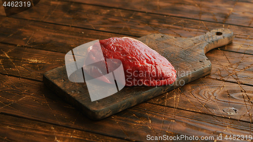 Image of Big fresh piece of meat laid on wooden cutting board