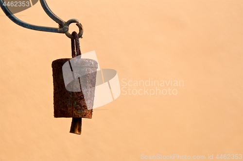 Image of old rusty bell hanging against blank wall